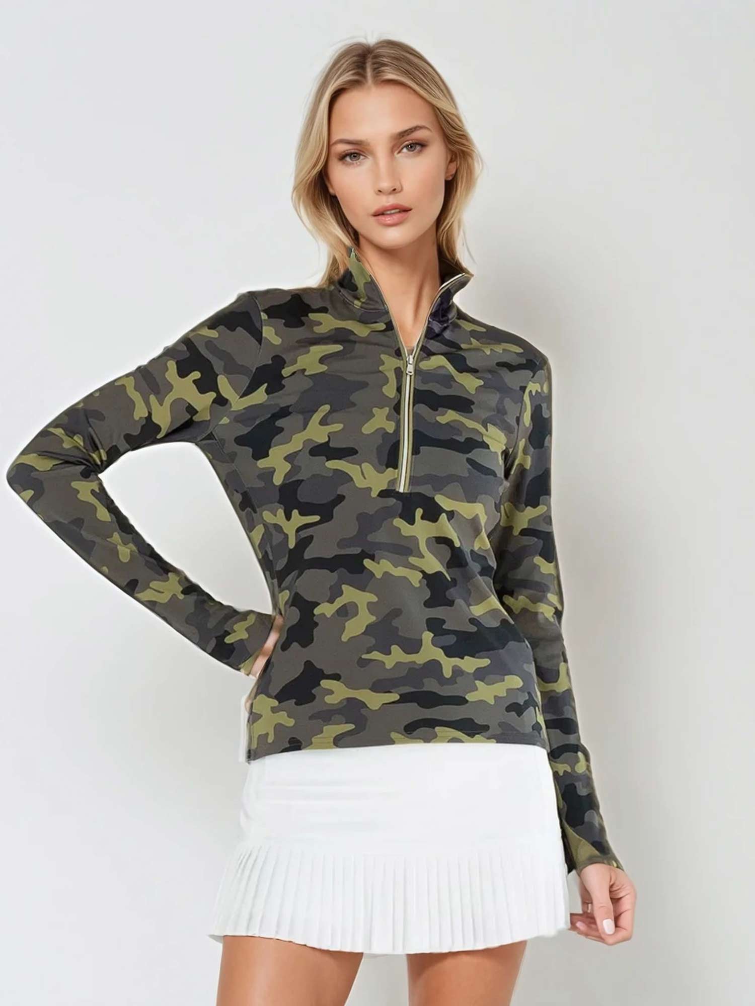 Woman wearing fitted camo print half-zip performance top with gold collar accents, thumbhole sleeves, and silver zipper detail, showcasing the versatile high collar design suitable for athletic and casual wear - front view with hand at the waist