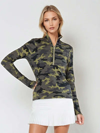 Woman wearing fitted camo print half-zip performance top with gold collar accents, thumbhole sleeves, and silver zipper detail, showcasing the versatile high collar design suitable for athletic and casual wear - front view with hand at the waist