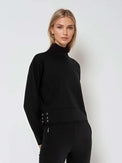 Woman wearing relaxed-fit funnel neck pullover with decorative silver zipper detail on left shoulder, showcasing the soft fabric drape and sporty-chic silhouette suitable for athletic and casual wear.  front 3/4 view