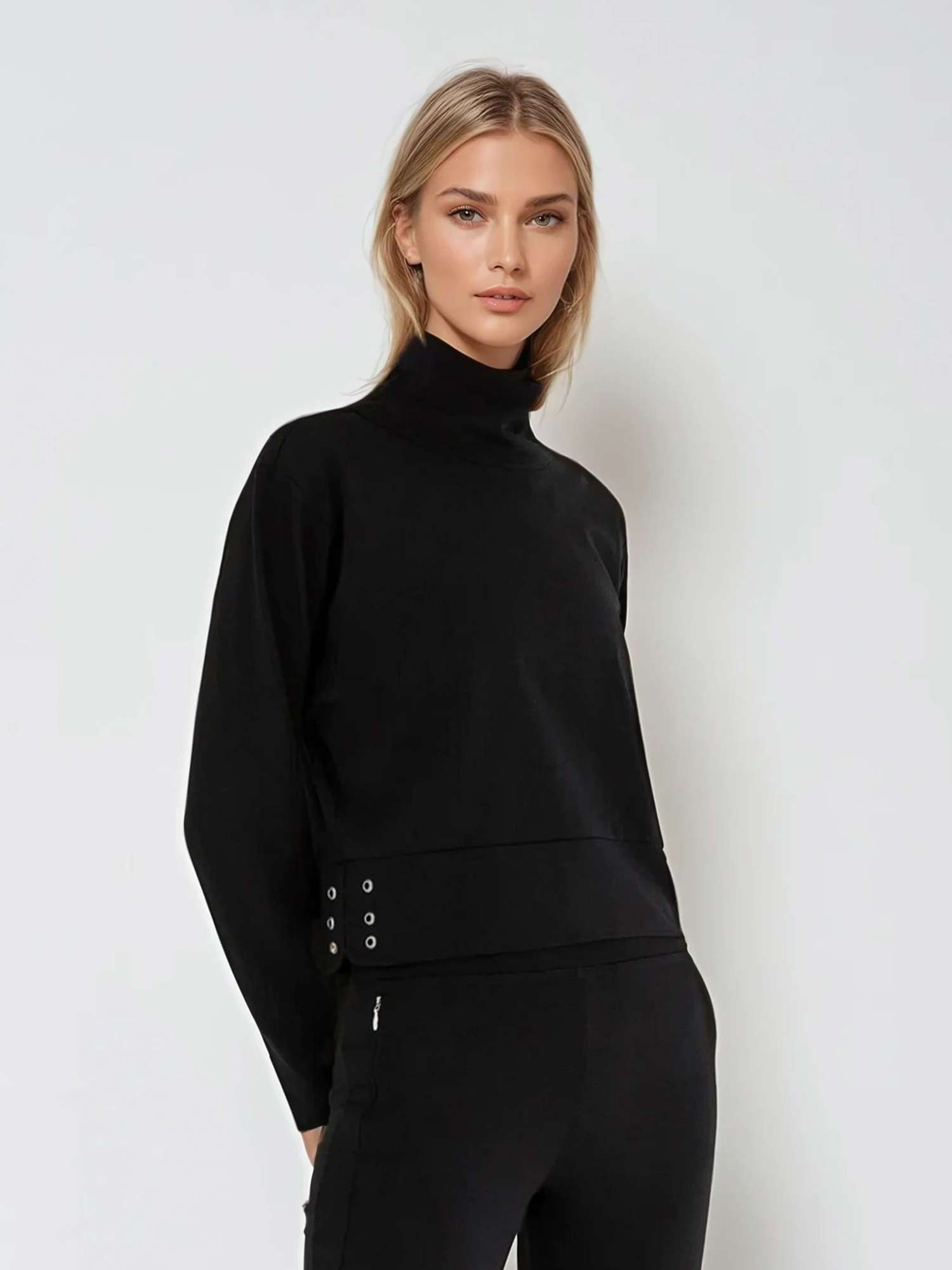 Woman wearing relaxed-fit funnel neck pullover with decorative silver zipper detail on left shoulder, showcasing the soft fabric drape and sporty-chic silhouette suitable for athletic and casual wear.  front 3/4 view