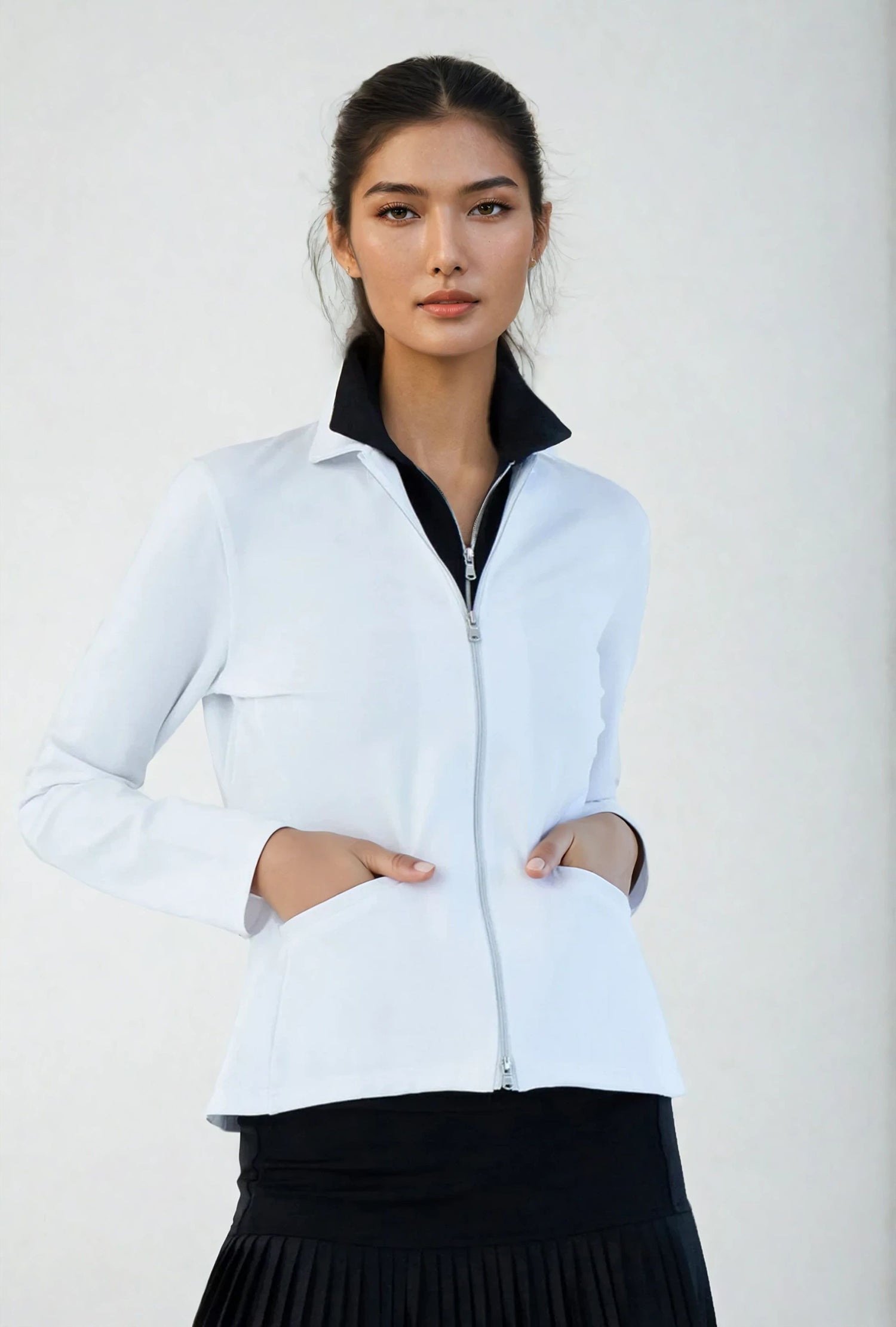 Woman wearing classic-fit Women's Active Blazer in white, showcasing the tailored silhouette with four-way stretch fabric suitable for both professional and active settings.  Front view with hands in pockets.