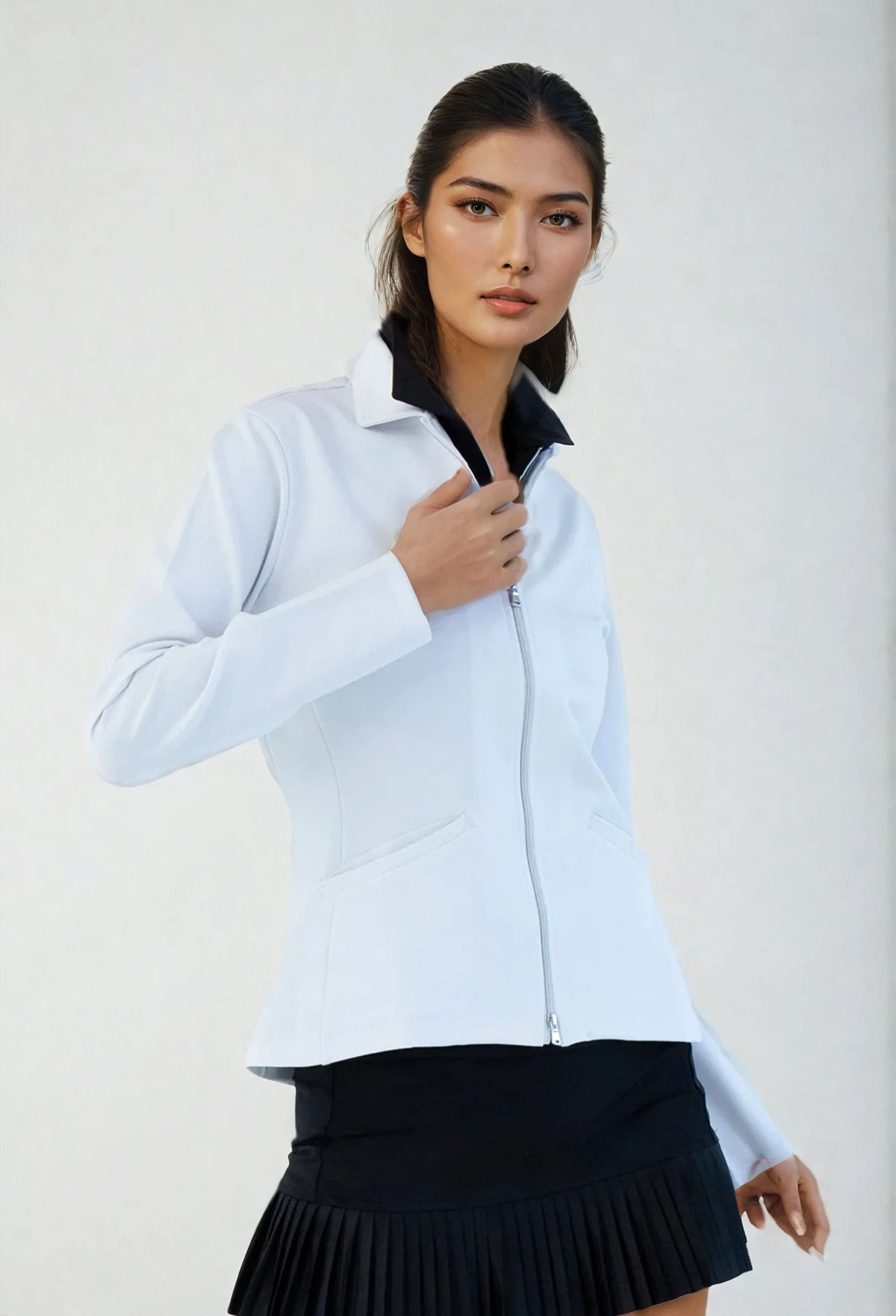 Woman wearing classic-fit Women's Active Blazer in white, showcasing the tailored silhouette with four-way stretch fabric suitable for both professional and active settings.  Front view with hand at the zipper.