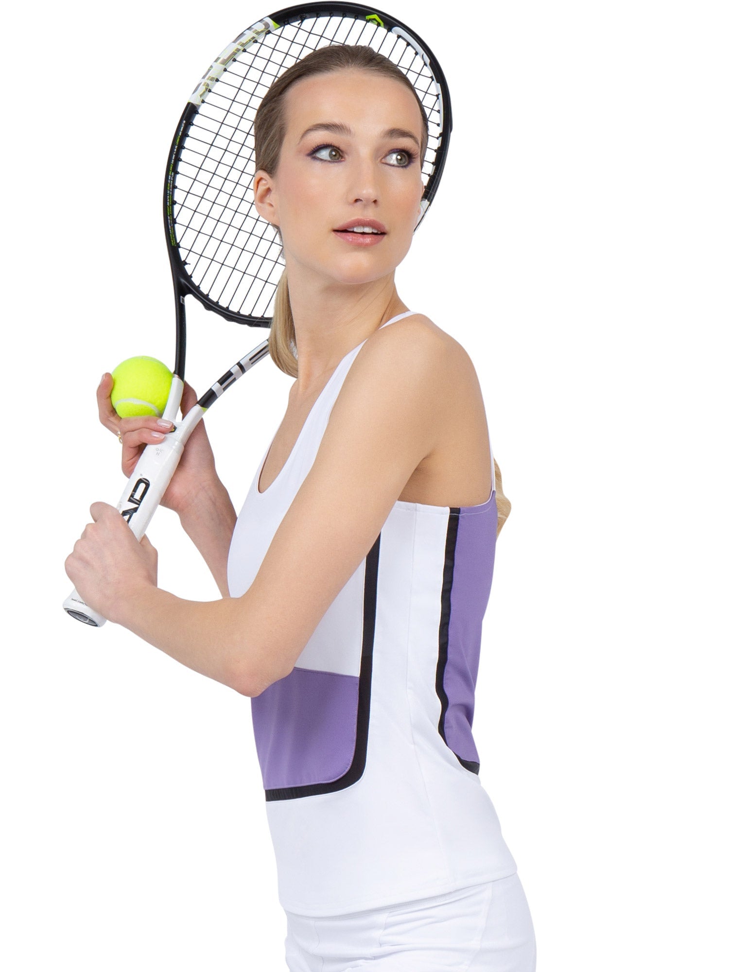 Side view of model wearing the baseline tank in white/lavender combo  by inPhorm NYC with one hand holding her tennis racket and the other holding a tennis ball