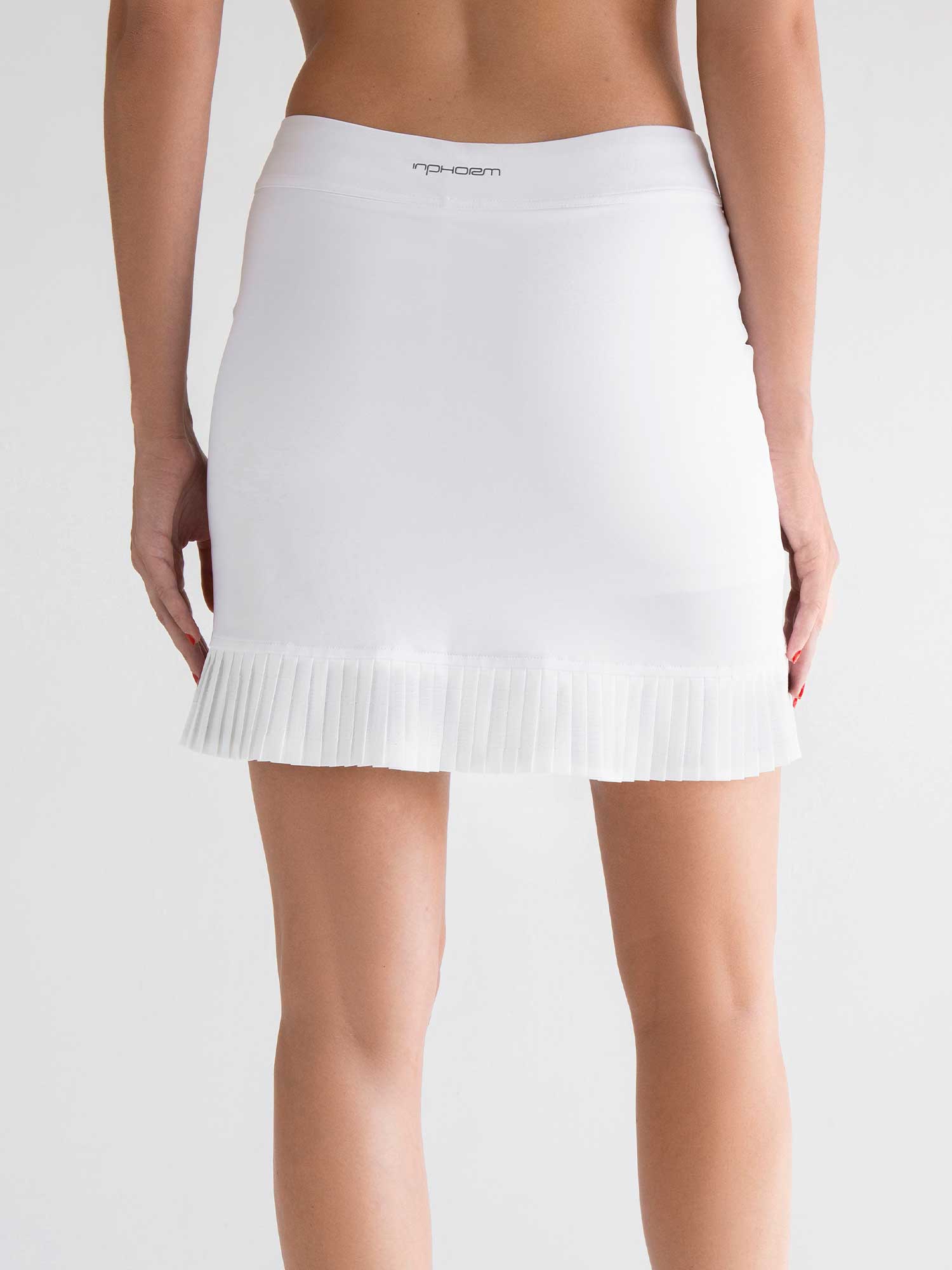 Back view of model wearing the Kai 17" pleated skirt in white by inPhorm NYC with her arms at her side