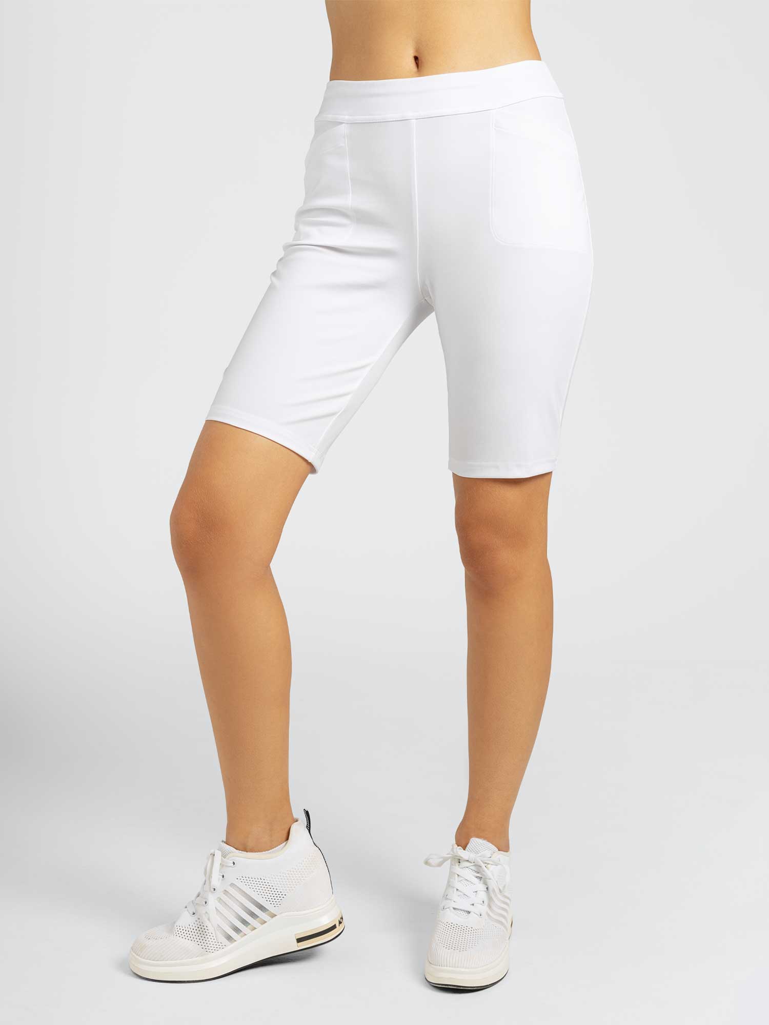 Front view of model wearing the tennis classic 13 1/2" pleated skirt in white by inPhorm NYC wearing white runners