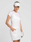 Front view of model wearing the Eloise 15" golf skirt in white by inPhorm NYC with her hand in her pocket wearing a white visor