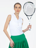 Front view of model wearing the Alexa performance sleeveless polo in white by inPhorm NYC one hand on her skirt and the other holding a tennis racket