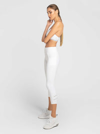 Side profile view of model wearing the Zone capri leggings in white and silver by inPhorm NYC with her arms crossed