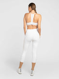 Back profile view of model wearing the Zone capri leggings in white and silver by inPhorm NYC with her arms at her side