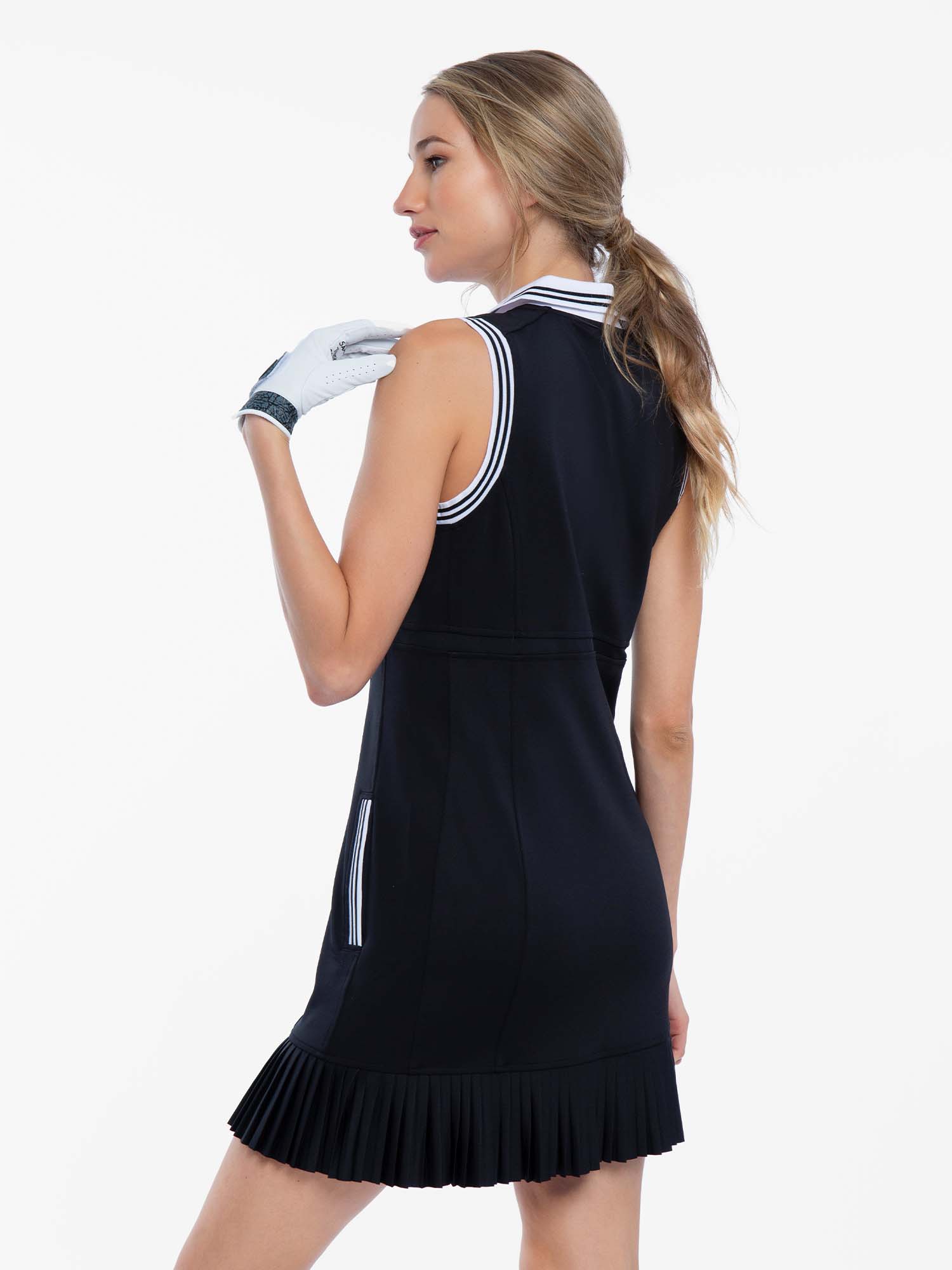 Back view of model wearing the Aubrey golf dress in black and white by inPhorm NYC wearing a white golf glove