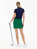 Back view of model wearing the Blake 17" golf skirt in ivy by inPhorm NYC holding a golf club