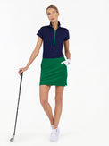 Front view of model wearing the Blake 17" golf skirt in ivy by inPhorm NYC holding a golf club