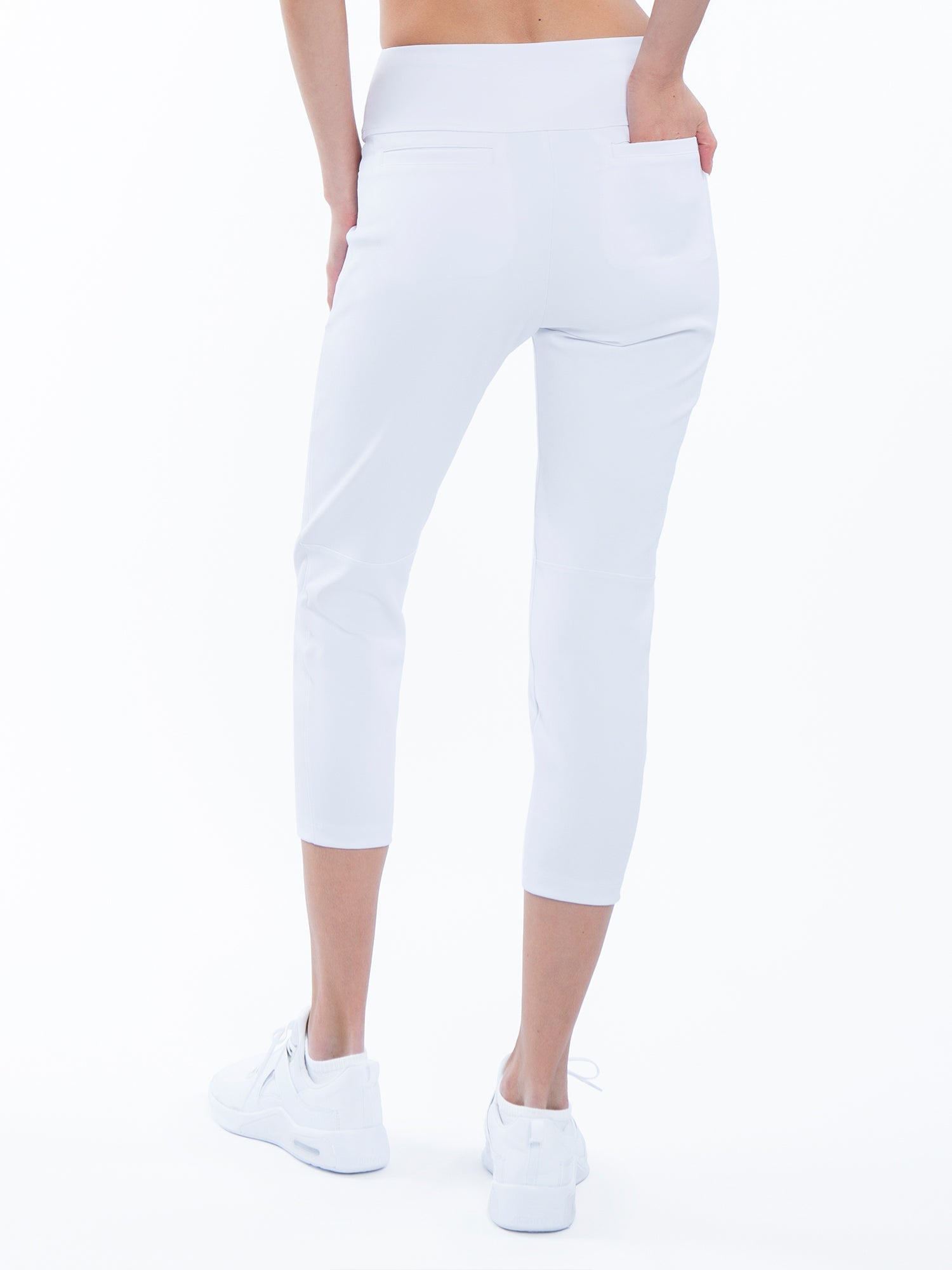 Back view of model wearing the quick dry golf 24" capri pants in white by inPhorm NYC with her hand in her pocket