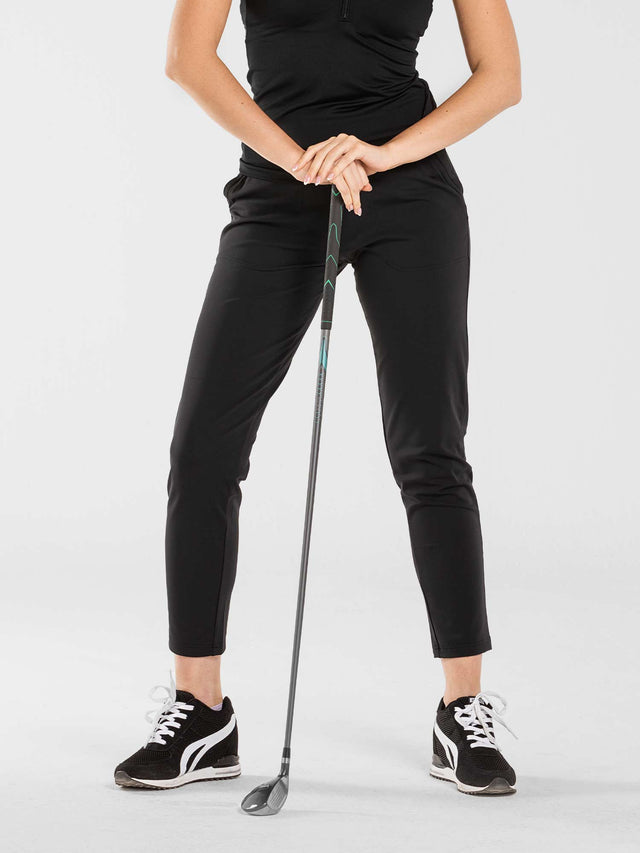 Front view of model wearing the swing Cleo pants in black by inPhorm NYC holding a golf club