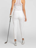 Back view of model wearing the swing Cleo pants in white by inPhorm NYC holding a golf club wearing a white top