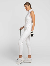 Side view of model wearing the swing Cleo pants in white by inPhorm NYC holding a golf club and wearing a black glove