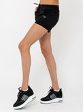 Side view of model wearing the active shorts in black by inPhorm NYC wearing matching black shoes