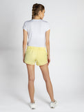 Back view of model wearing the tennis active shorts in lemonade by inPhorm NYC with her hands at her side