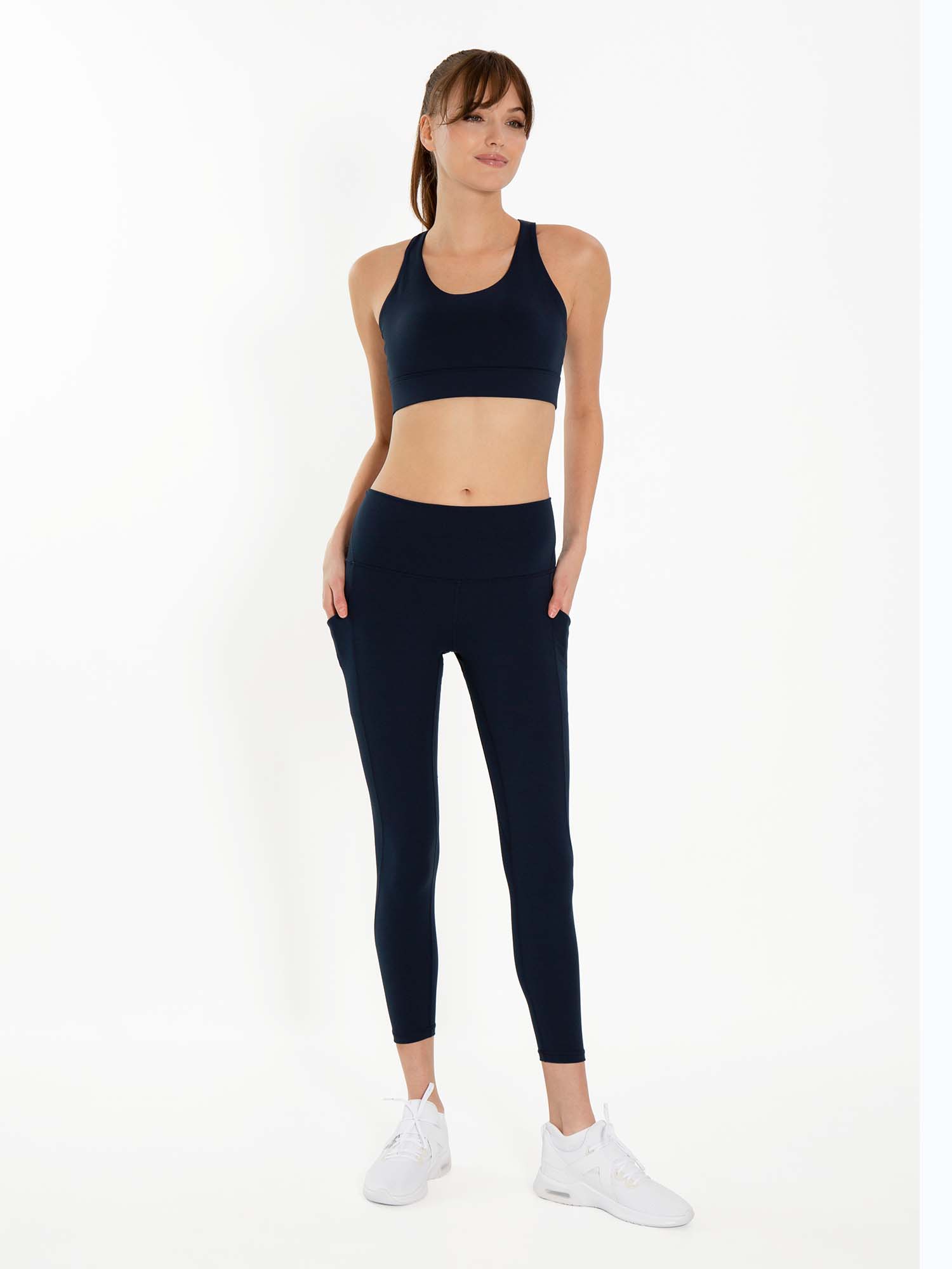 Front view of model wearing the Ashley 7/8 legging in black by inPhorm NYC with both hands in her pockets