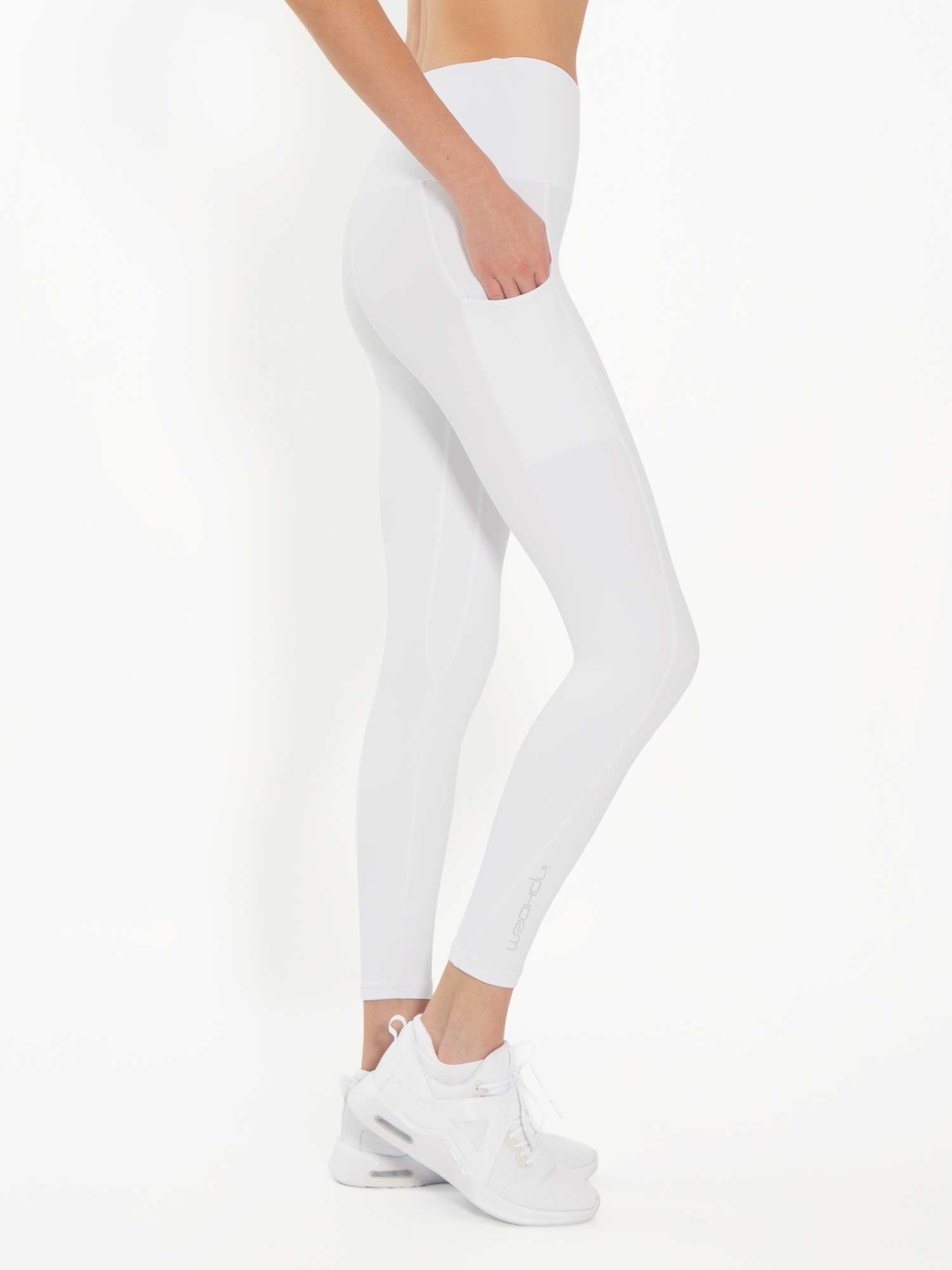 Side view of model wearing the Ashel 7/8 leggings in white by inPhorm NYC with one hand in her pocket