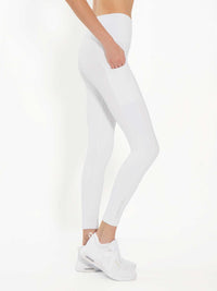 Side view of model wearing the Ashel 7/8 leggings in white by inPhorm NYC with one hand in her pocket