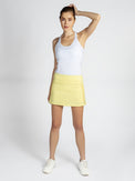 Front view of model wearing the Aubrey 13 1/2 tennis skirt in lemonade by inPhorm NYC with one hand on her head