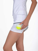 Side view of model wearing the Chloe 15" asymmetrical skirt in white and black by inPhorm NYC holding a yellow tennis ball