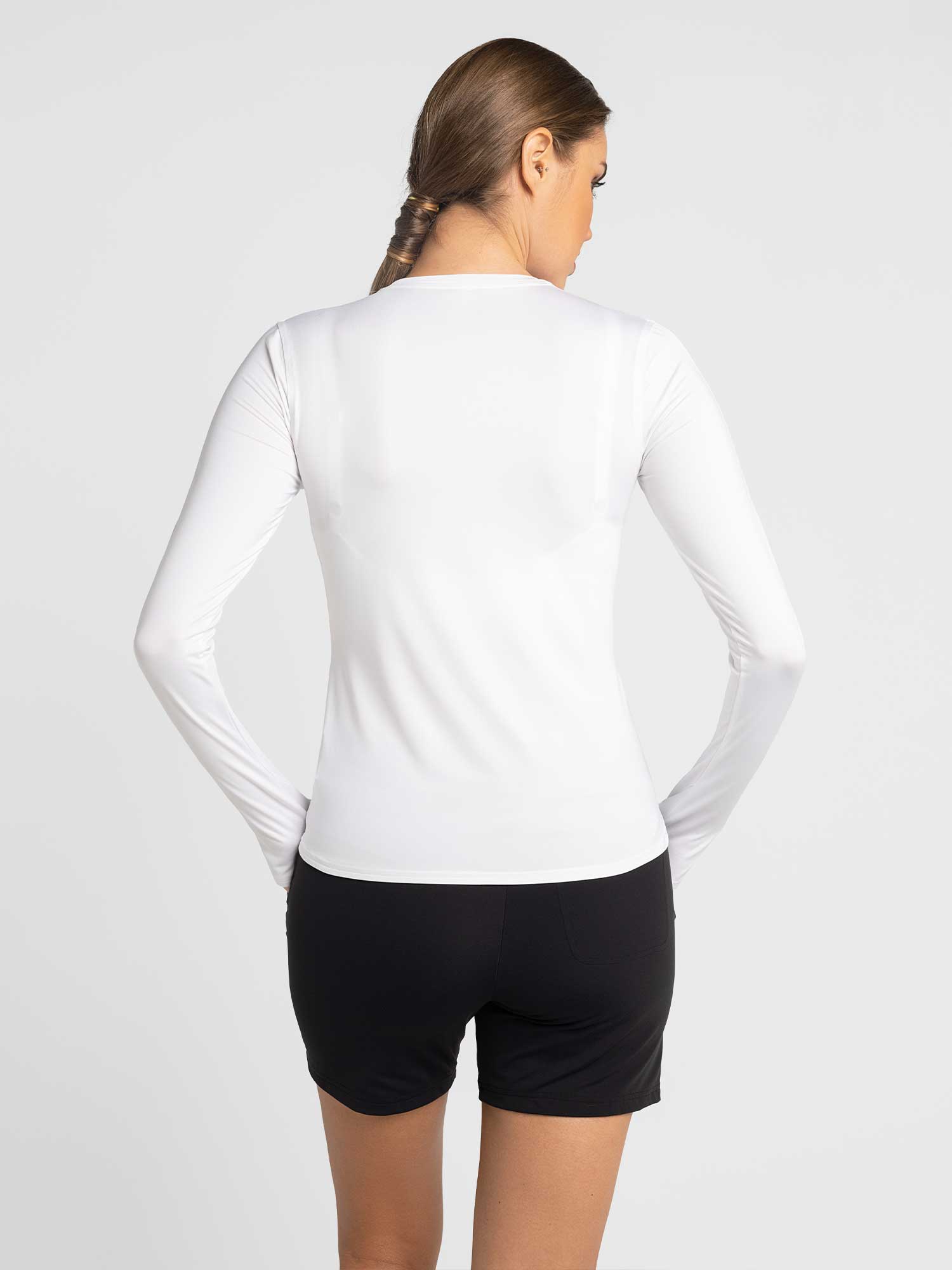 Back view of model wearing the classic long sleeve crew in white by inPhorm NYC with her hands in her pockets