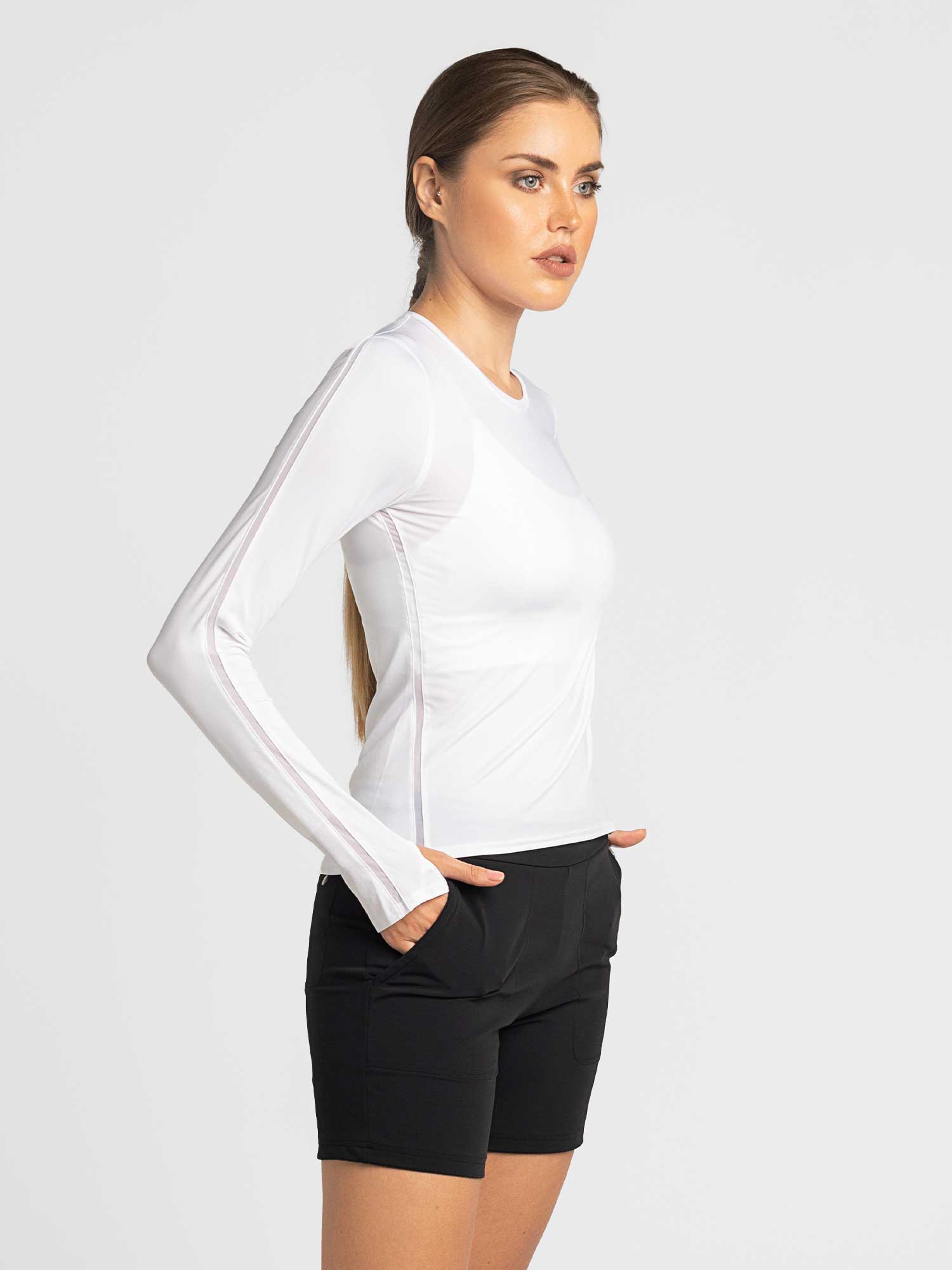 Side view of model wearing the classic long sleeve crew in white by inPhorm NYC with one hand in her pocket