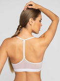 Back view of model wearing the classic strappy bra in white by inPhorm NYC with her hands on her head