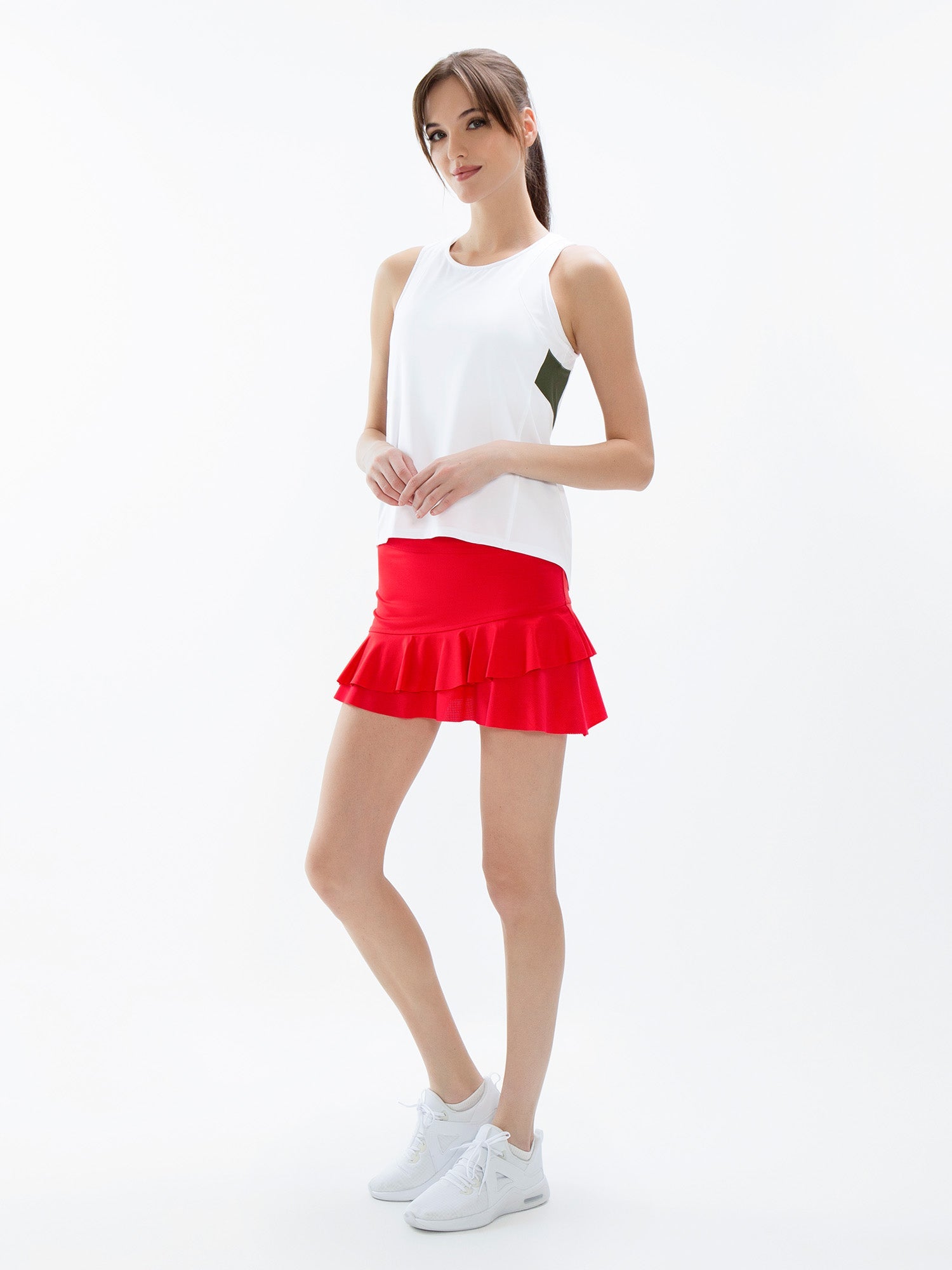 Front view of model wearing the courtside charm tennis skirt in poppy by inPhorm NYC with her hands together