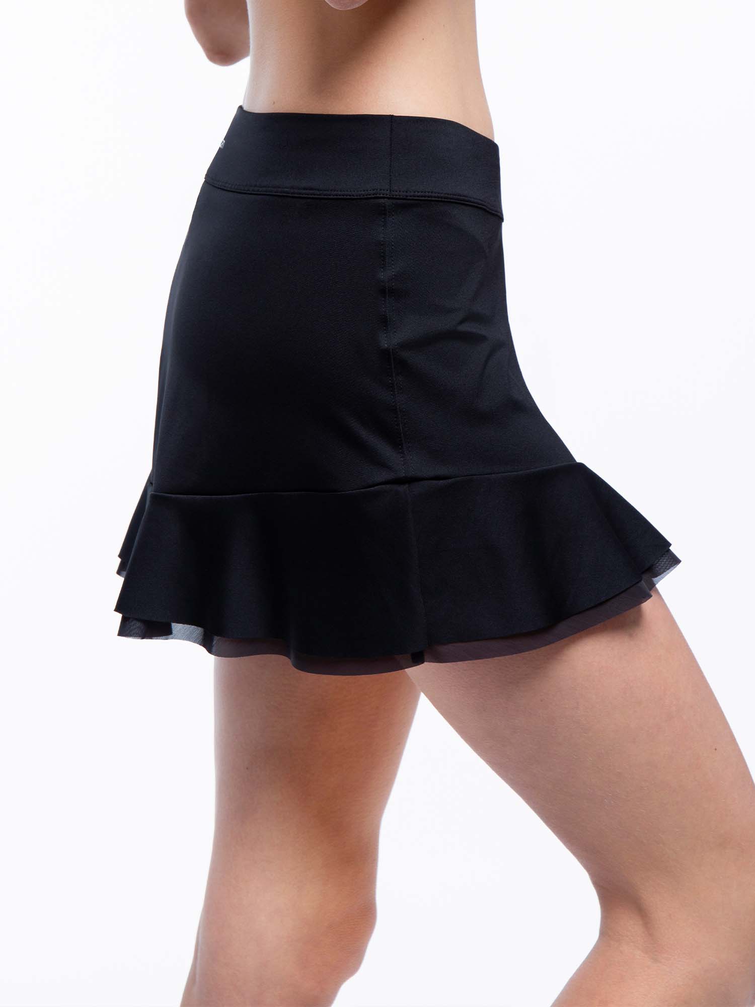 Side view of model wearing the Emma 13 1/2 " tennis skirt in black by inPhorm NYC