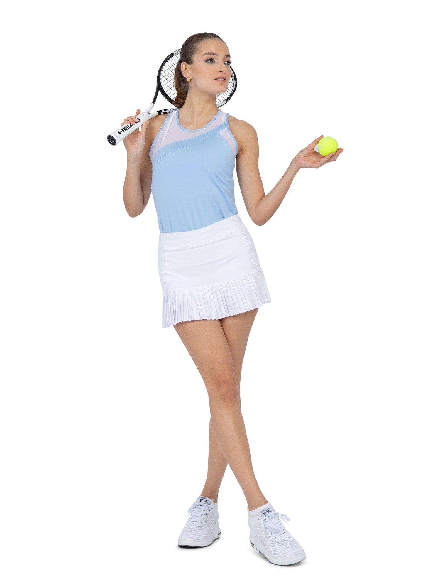 Front view of model wearing the Emma tank in bluebell by inPhorm NYC with her hands at her side holding a tennis ball and a tennis racket with her legs crossed