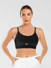 Front view of model wearing the essential bra in black by inPhorm NYC with her hands in her pockets wearing white pants