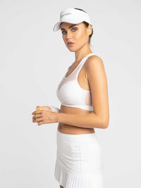 Side view of model wearing the eyelet mesh seamless bra in white by inPhorm NYC wearing a white visor