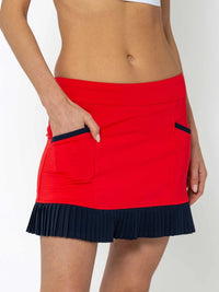 Front view of model wearing the Kai 15" pleated skirt in poppy and midnight by inPhorm NYC with one hand in her pocket