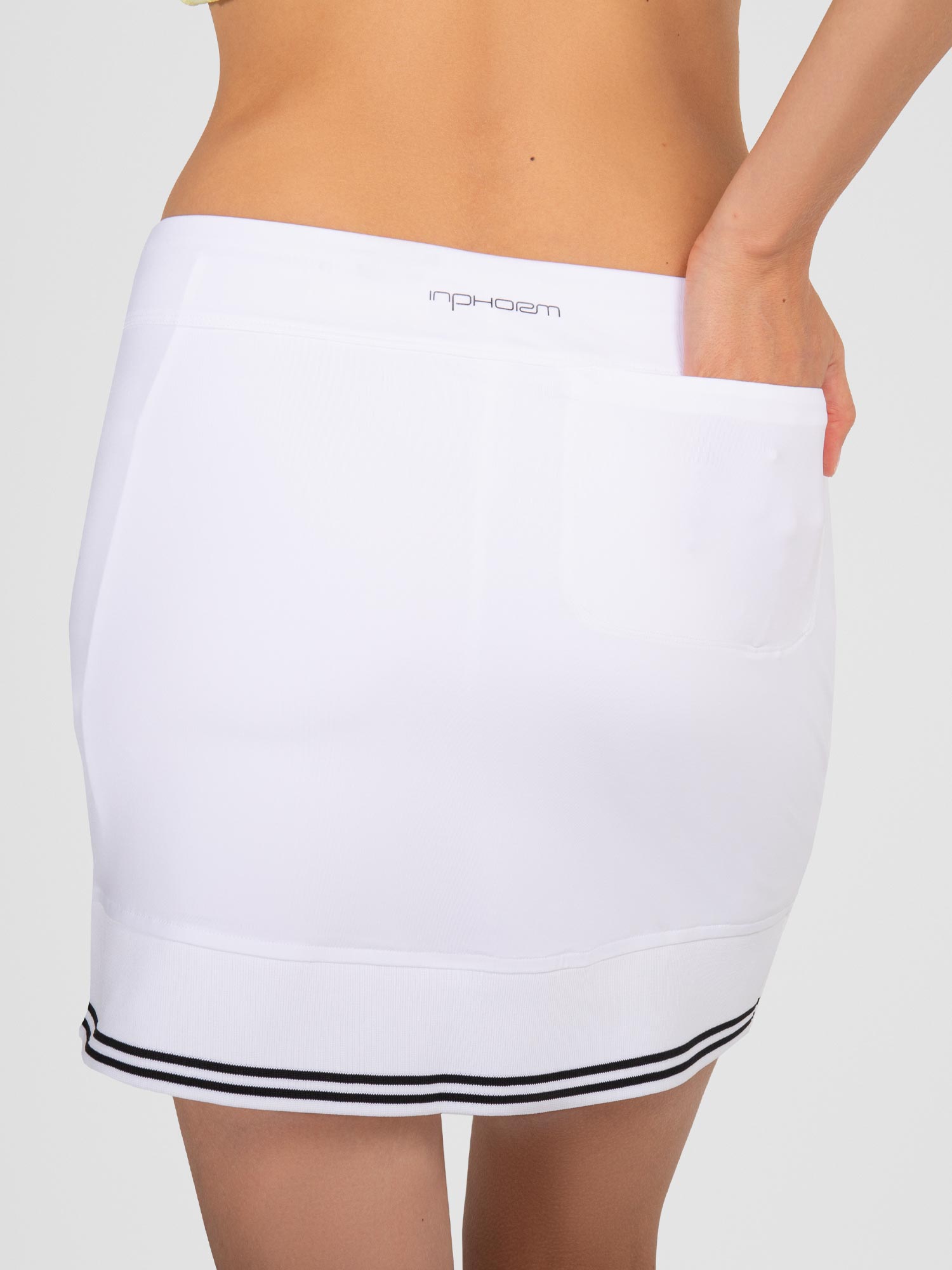 Back view of model wearing the Lilian 15" skirt in white/black by inPhorm NYC with her hand in her back pocket