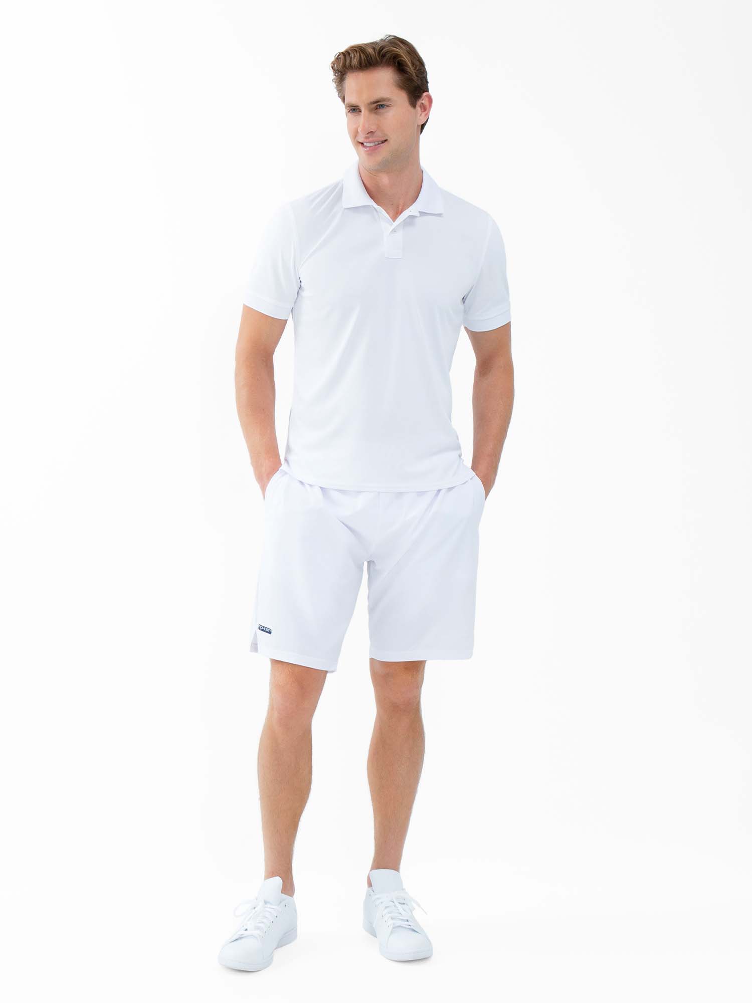 Front view of model wearing the performance mens classic tennis rib collar polo in white poppy and militare by inPhorm NYC wearing white shoes with his hands in his pockets