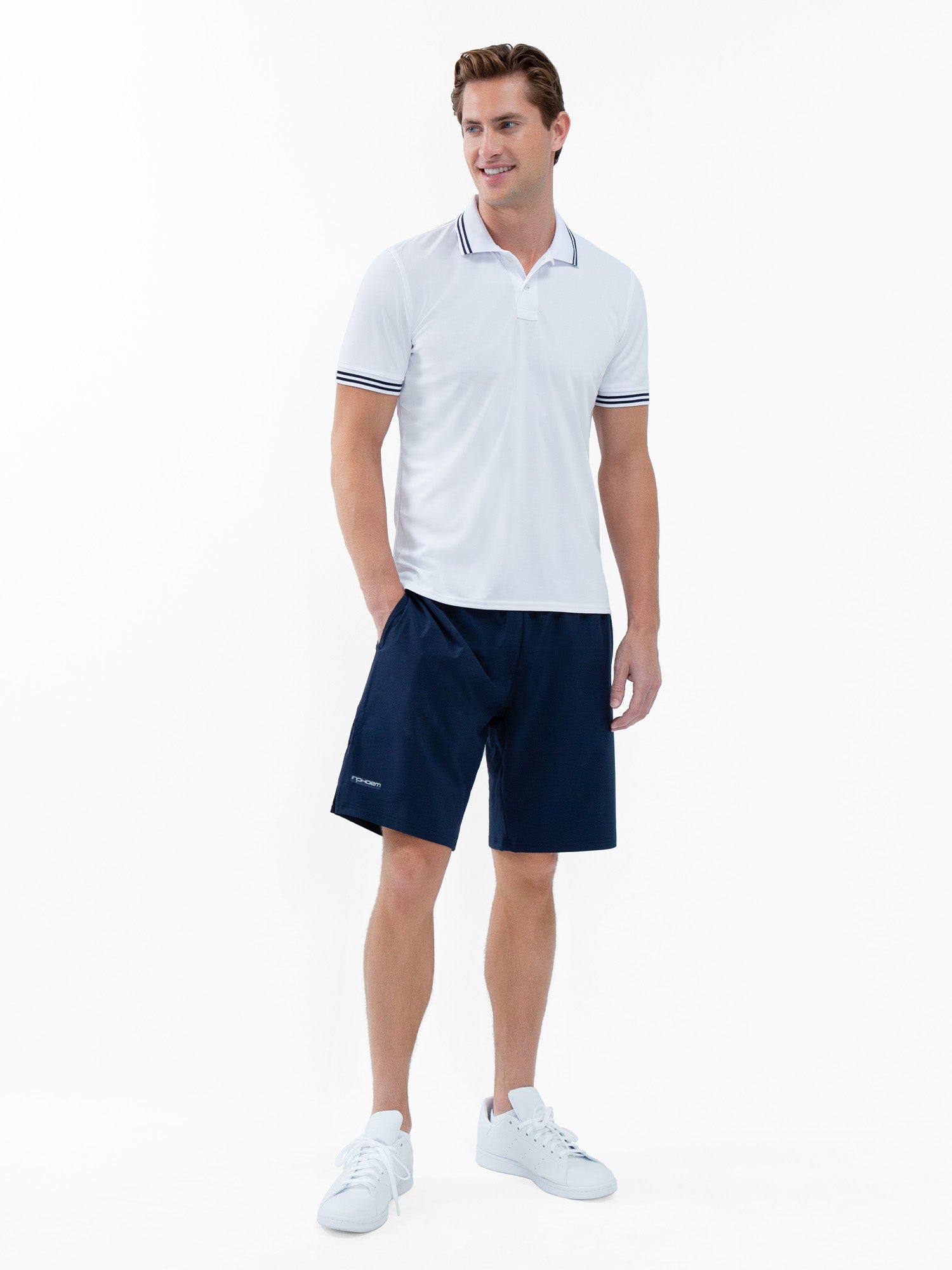 Front view of model wearing the mens classic tennis rib collar polo in white and midnight by inPhorm NYC wearing shorts with his hands at his side