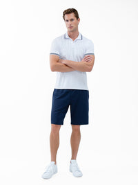 Front view of model wearing the mens classic tennis rib collar polo in white and midnight by inPhorm NYC with his arms crossed