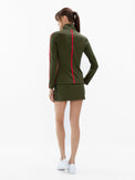 Back view of model wearing the motion knit jacket in militaire and poppy by inPhorm NYC with her hand in her pocket