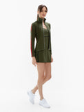 Front view of model wearing the motion knit jacket in militaire and poppy by inPhorm NYC with her hands at her side wearing white shoes