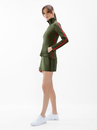 Front view of model wearing the motion knit jacket in militaire and poppy by inPhorm NYC with her hand in her pocket