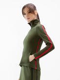 Front view of model wearing the motion knit jacket in militaire and poppy by inPhorm NYC with her hands in her pockets