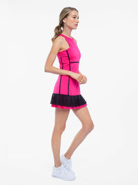 Side view of model wearing the Nora tennis dress in fuchsia and black by inPhorm NYC with her arms bent at her tummy