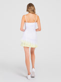 Back view of model wearing the pearl adjustable strap tennis dress in white zest ombre a by inPhorm NYC with her amrs bent