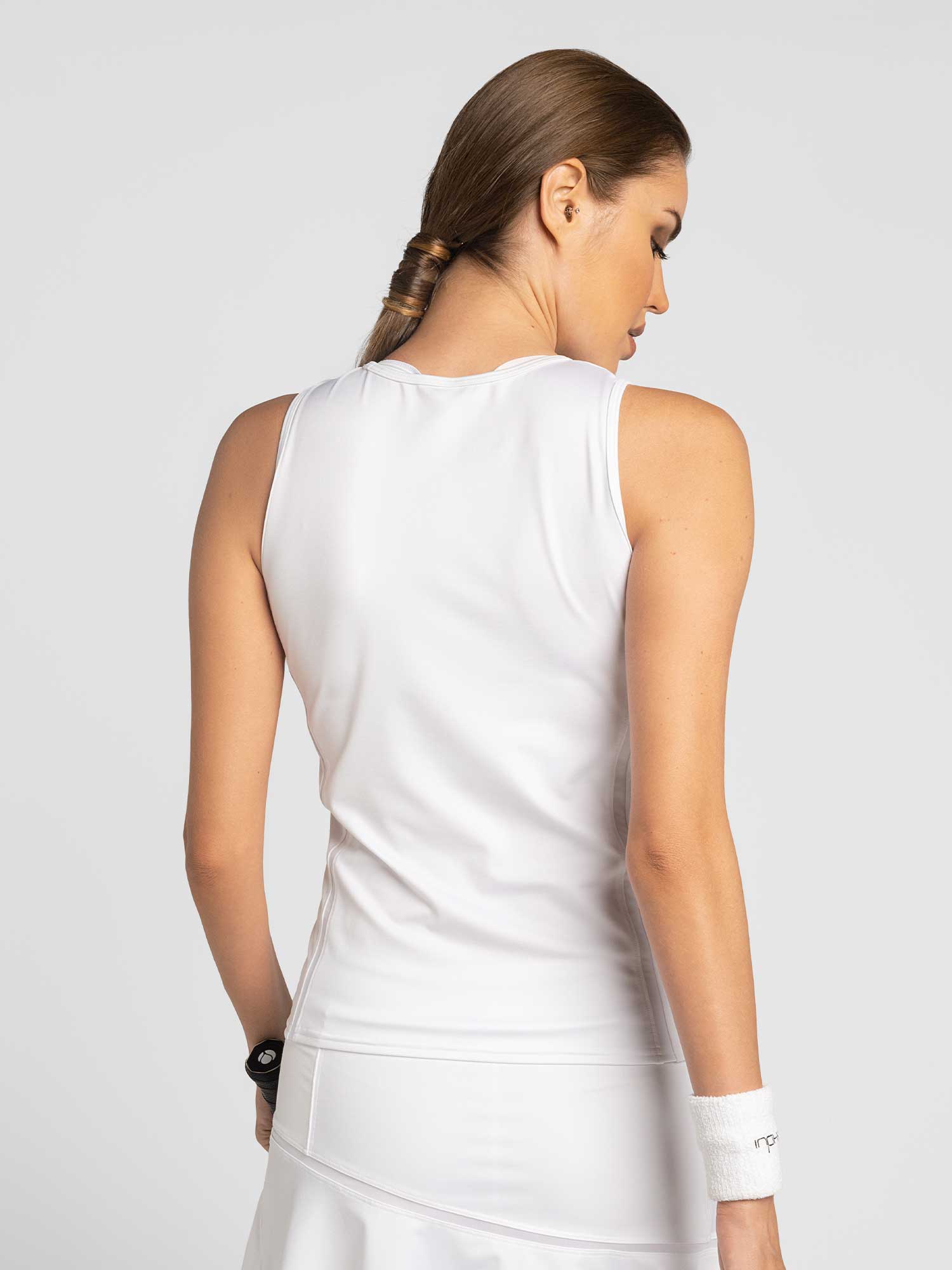 Back view of model wearing the classic performance active tank in white by inPhorm NYC with her hands at her side