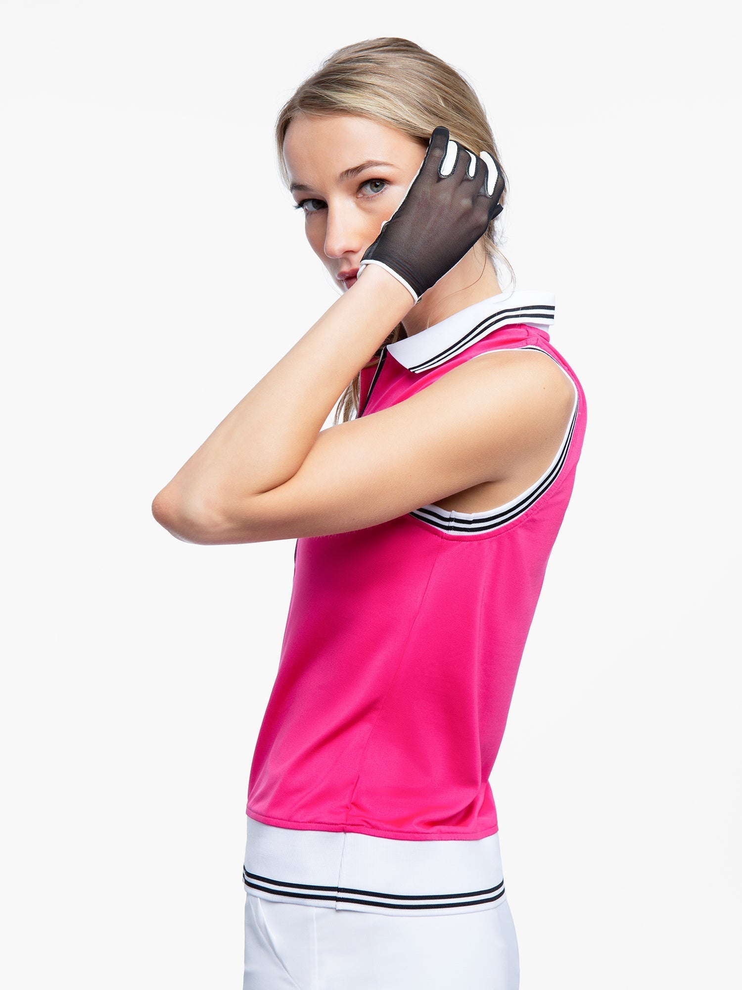 Side view of model wearing the Phoebe sleeveless polo in fuchsia combo by inPhorm NYC wearing a black glove with her hand on her face