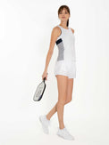 Side view of model wearing the Blaire tank in white/midnight pearl by inPhorm NYC with her hands at her side holding a tennis racket