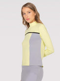 Front view of model wearing the Riley performance mock neck in zest combo by inPhorm NYC with one hand behind her back